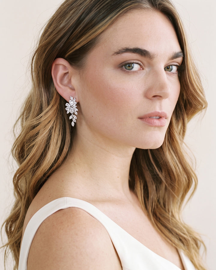 Bride with blonde waves in a white gown wearing Vivian asymmetrical floral earrings
