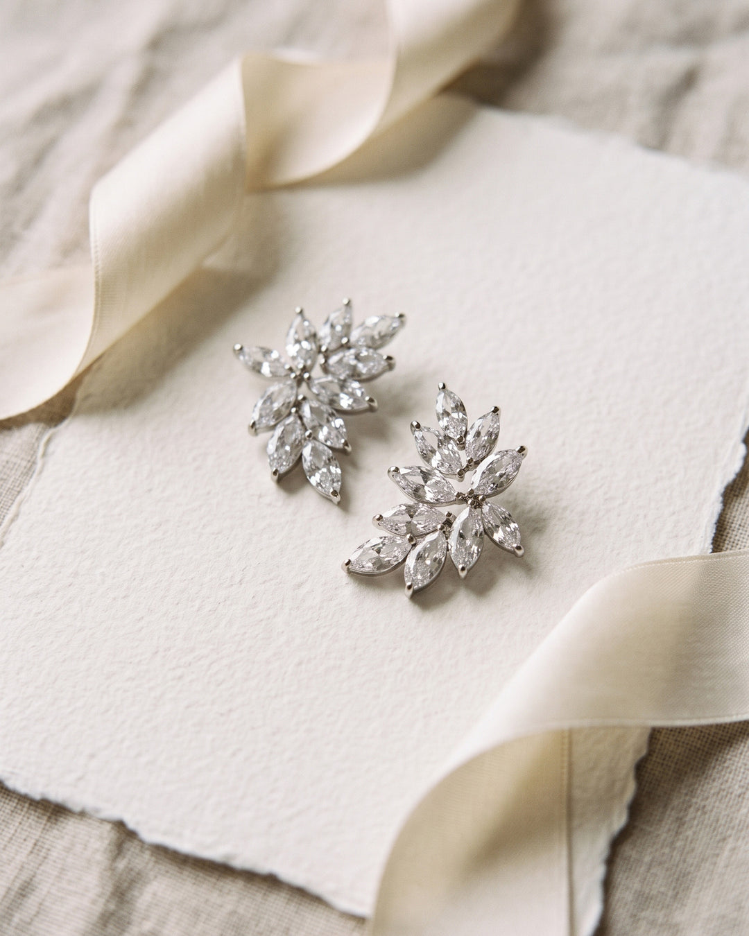 Farah silver CZ statement stud earrings with marquise stones in a leafy cluster on cream paper