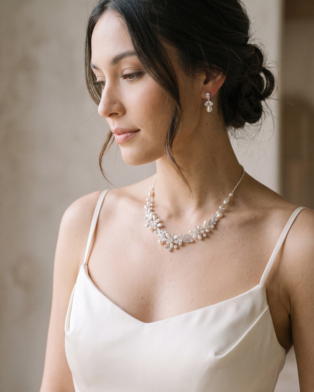 Bride with an updo in profile wearing the Delicate Pearl necklace and earrings