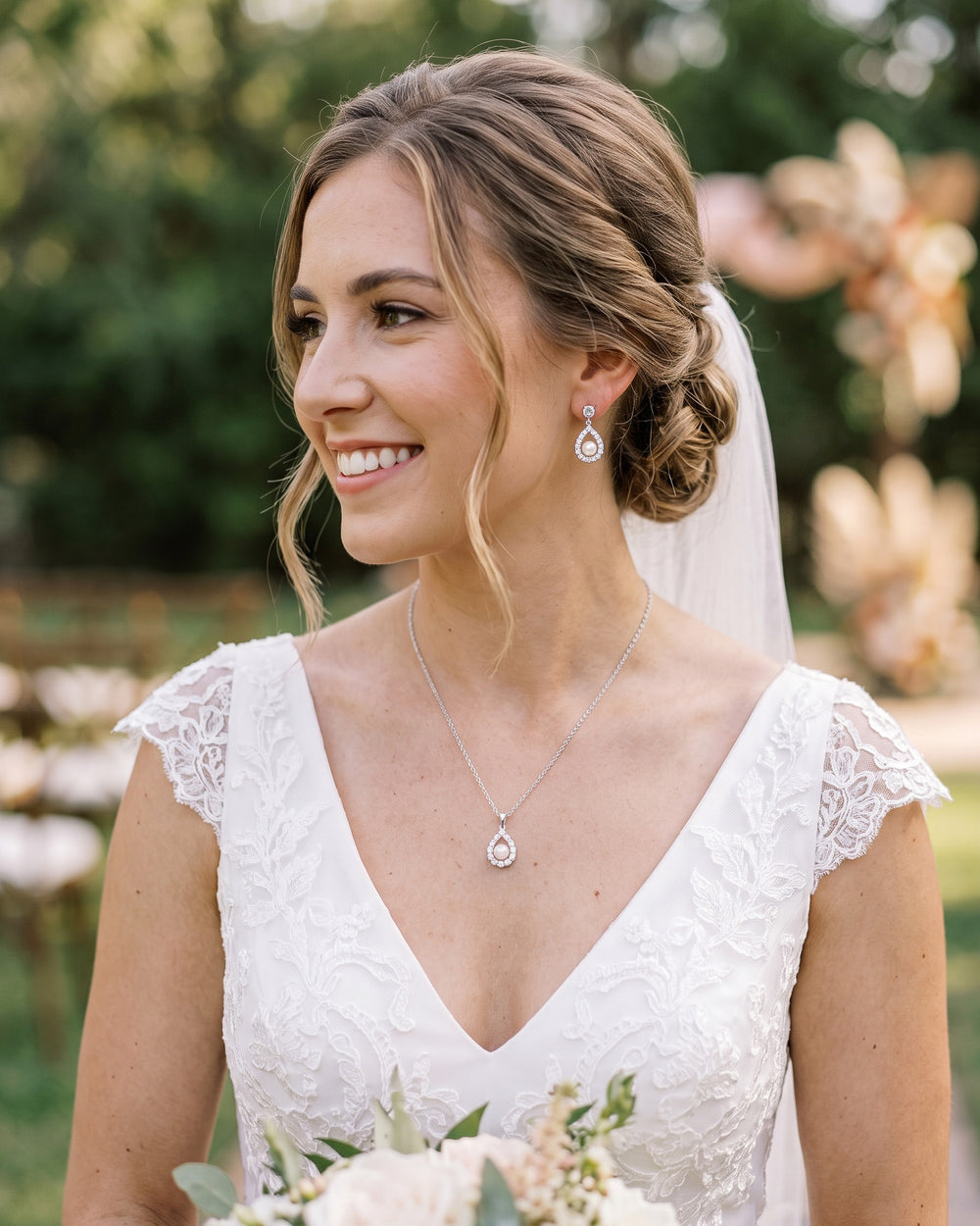 Bride with a veil and low updo wearing the Elegance pearl halo earrings and pendant