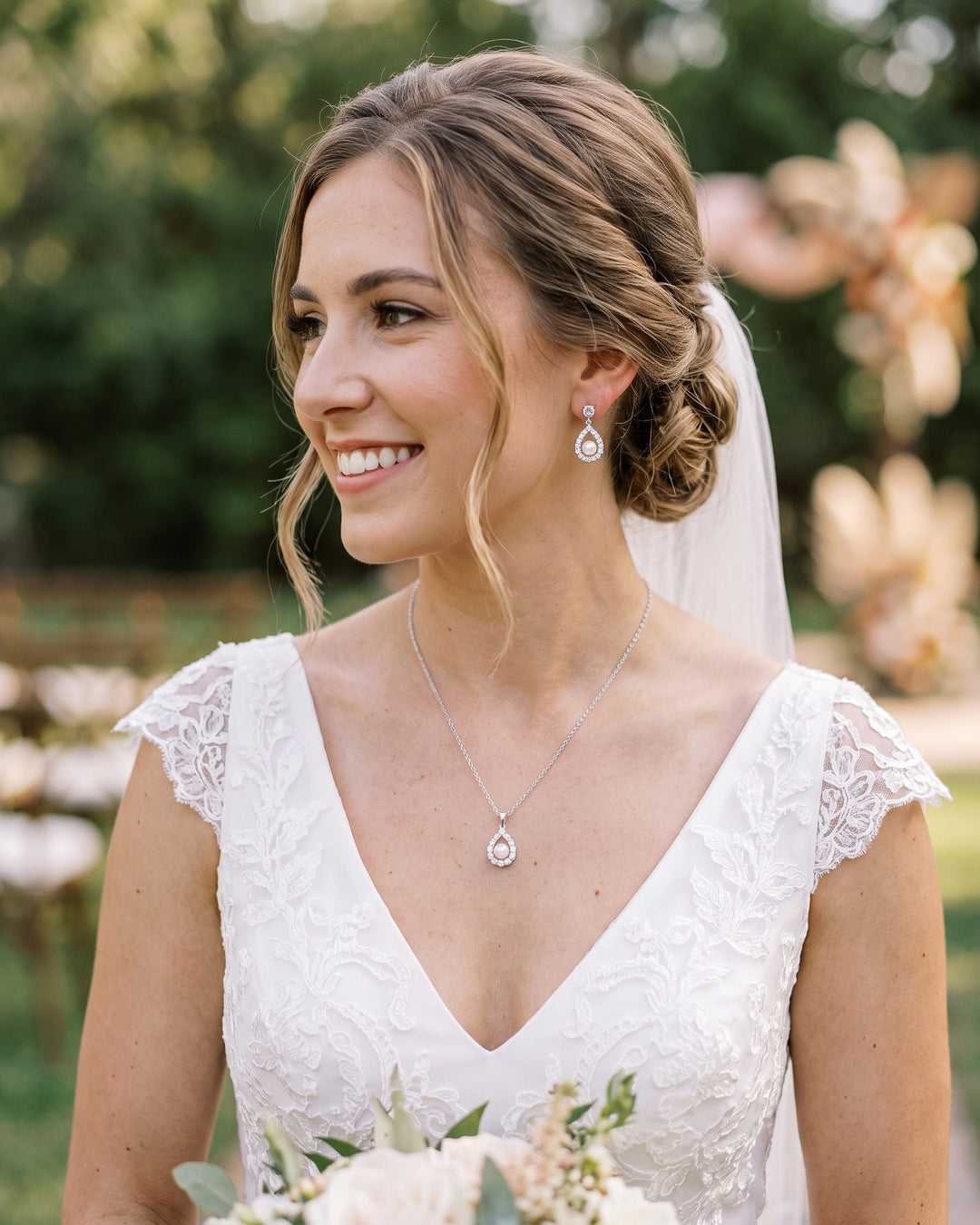 Bride with a veil and low updo wearing the Elegance pearl halo earrings and pendant