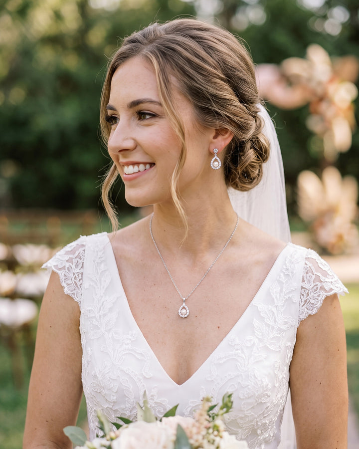 Bride with a veil and low updo wearing the Elegance pearl halo earrings and pendant