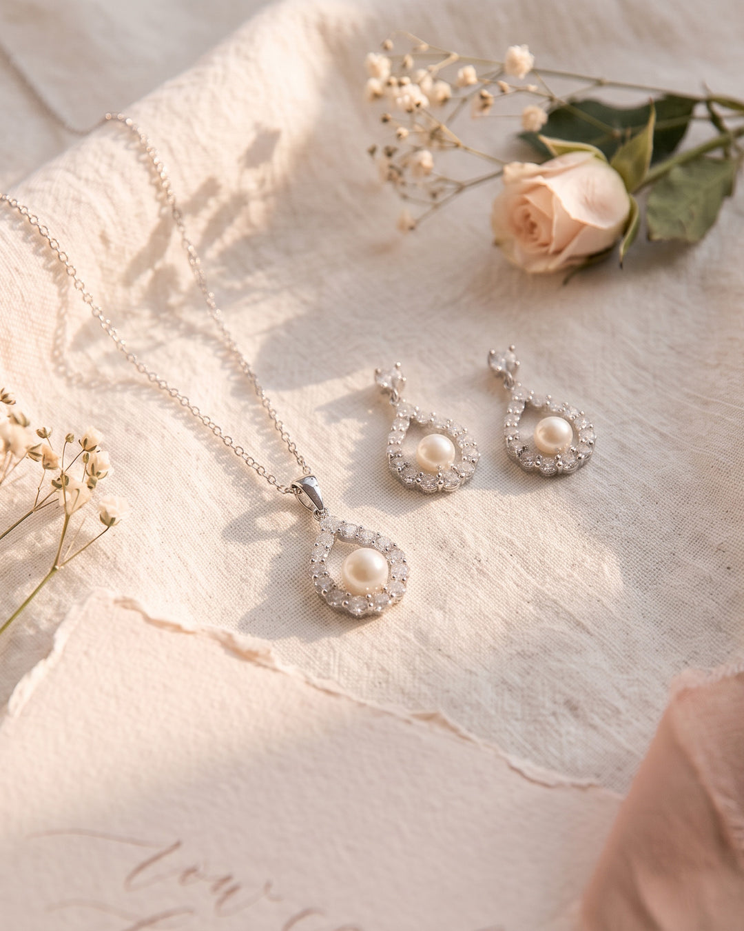 Silver Elegance necklace and earrings on ivory linen with a blush rose and baby's breath