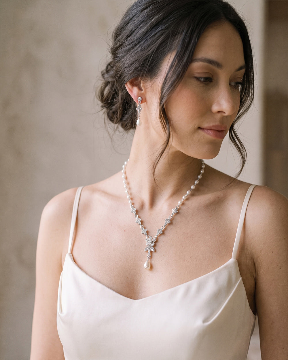 Bride with an updo in profile wearing the Primrose pearl drop necklace and earrings