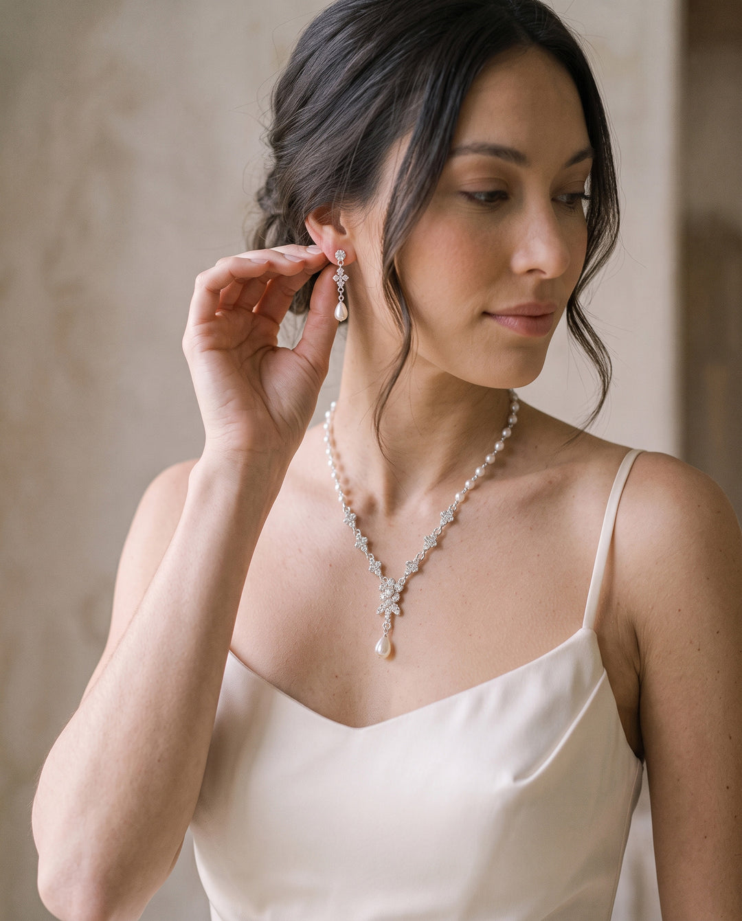 Bride touching her Primrose pearl drop earring, matching necklace at her neckline