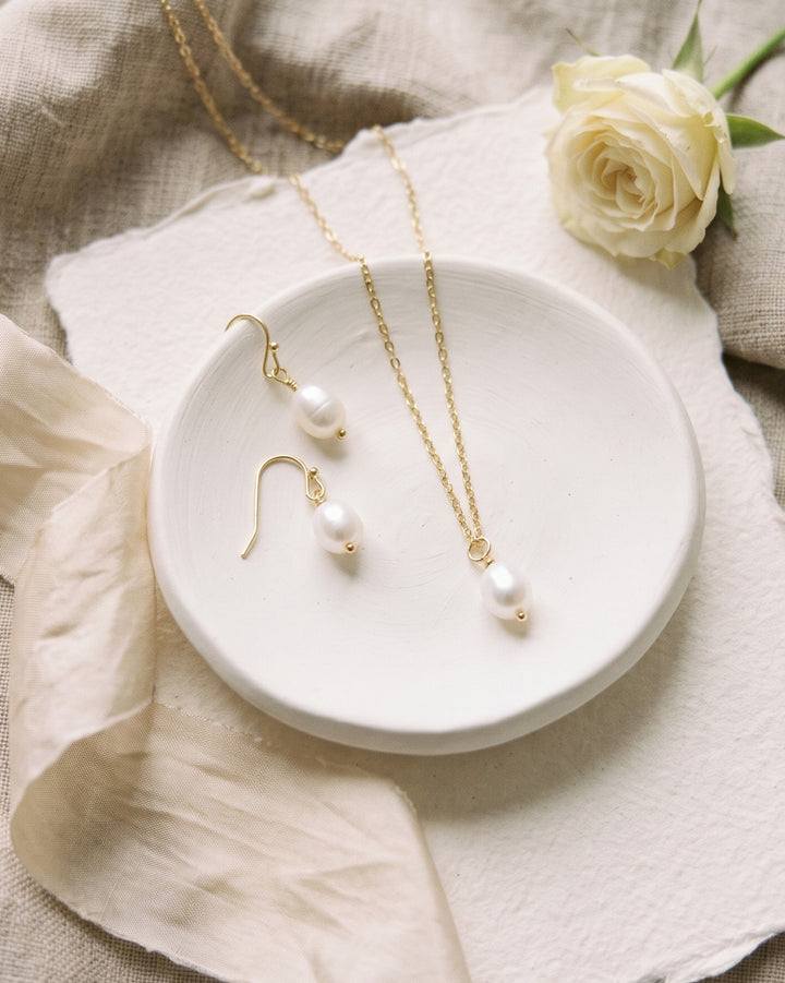 Simple Pearl Pendant Set in a white ceramic dish with a white rose