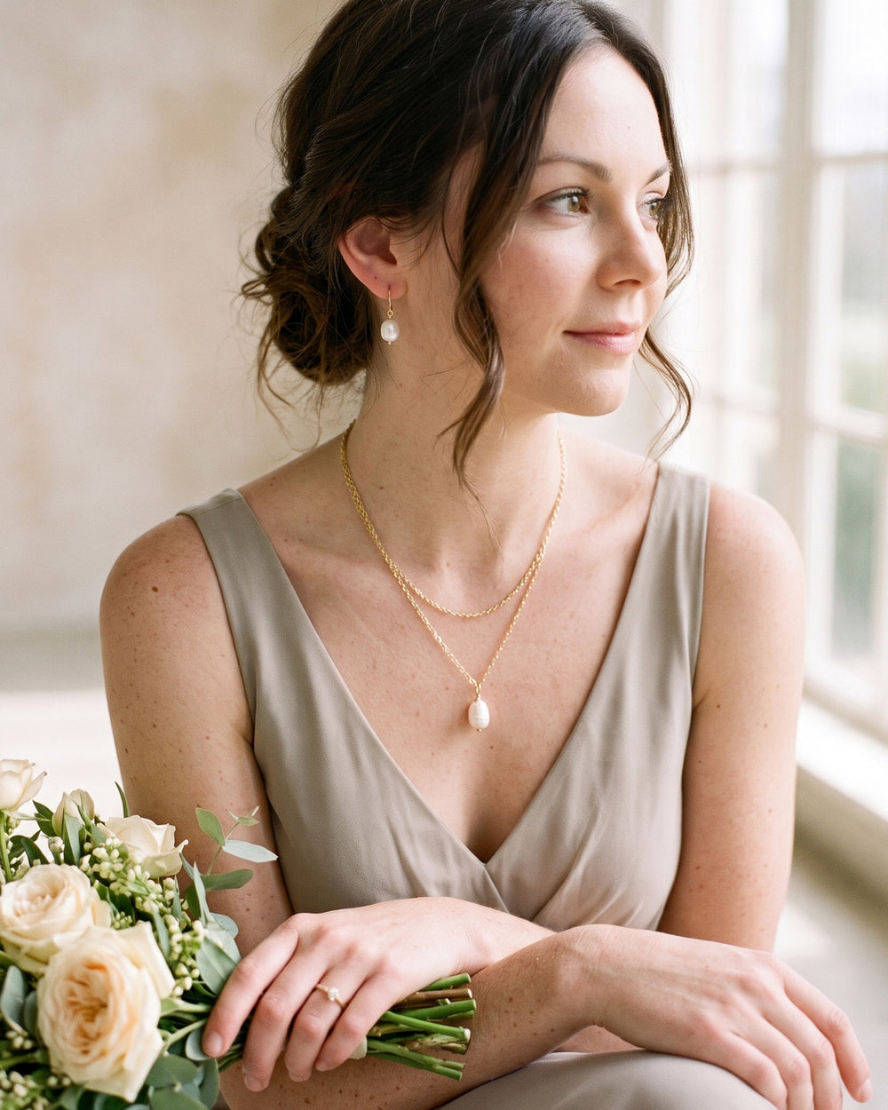 Bridesmaid in a soft greige dress wearing the layered gold pearl drop necklace and earrings