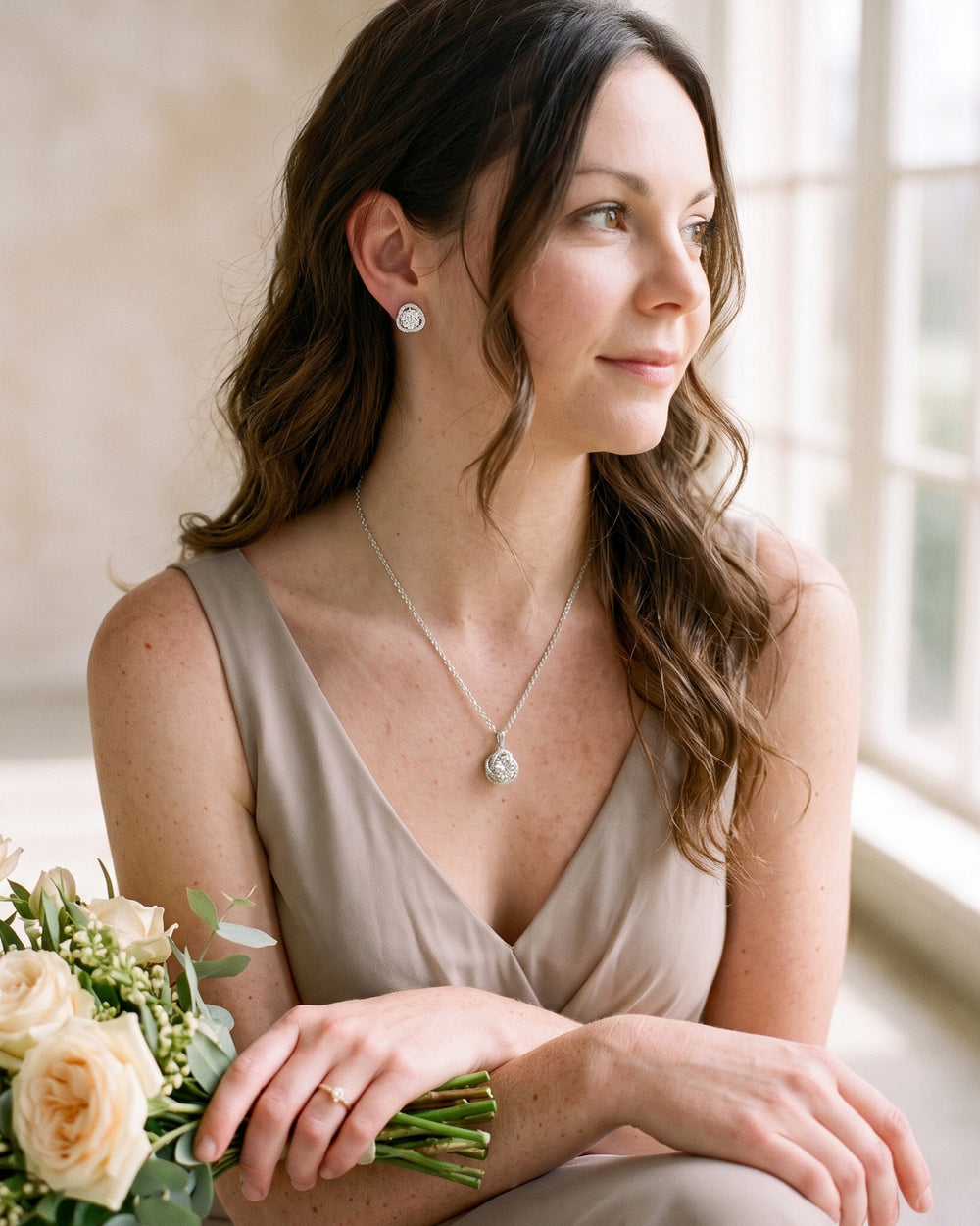 Bridesmaid in a soft greige dress wearing the Teagan halo pendant and stud earrings
