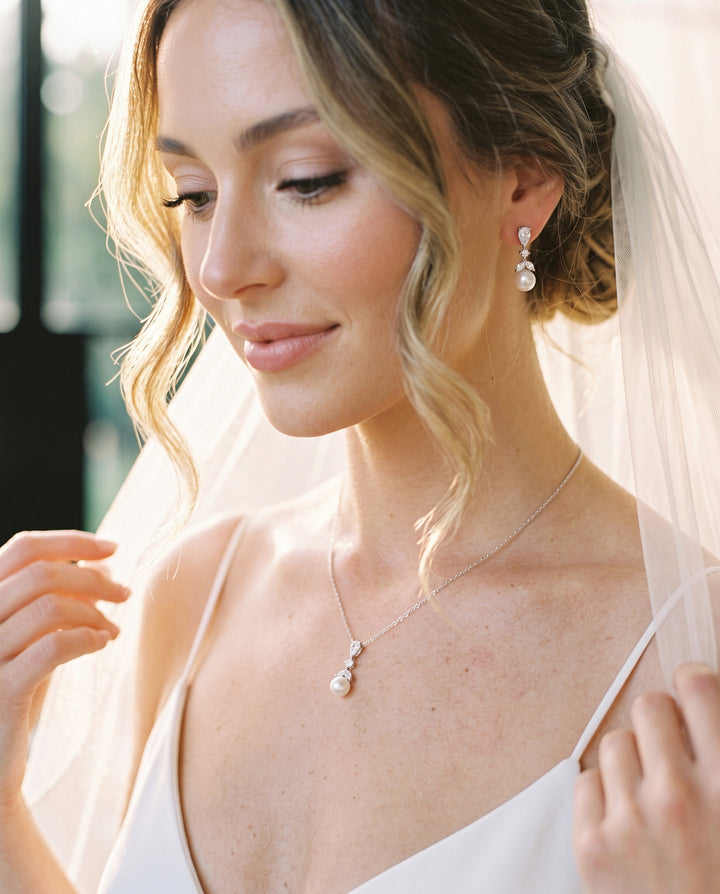 Bride in a veil wearing the Kelsey pearl pendant necklace and matching pearl drop earrings