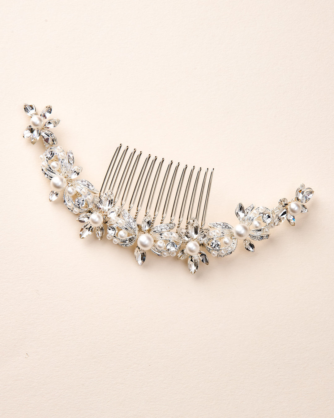 Silver hair comb with pearls and crystals on a beige background