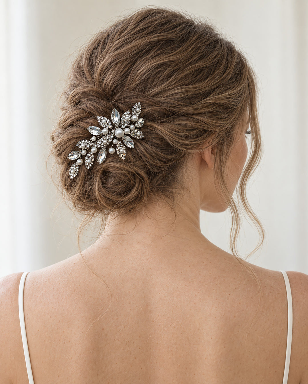 Bride with an updo wearing a silver pearl and rhinestone comb tucked into the back of her hair