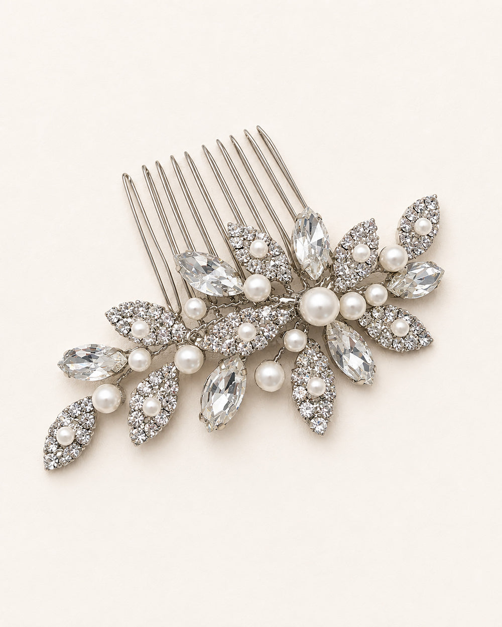 Close-up of a silver wedding comb showing rhinestone leaf clusters and a center pearl