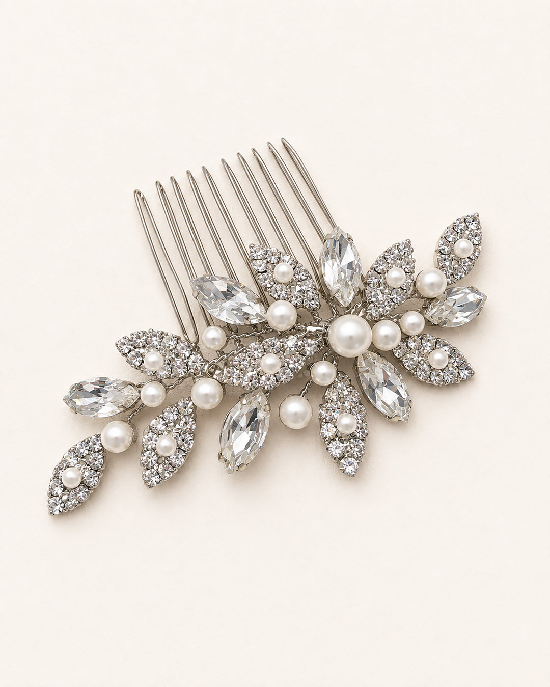 Close-up of a silver wedding comb showing rhinestone leaf clusters and a center pearl