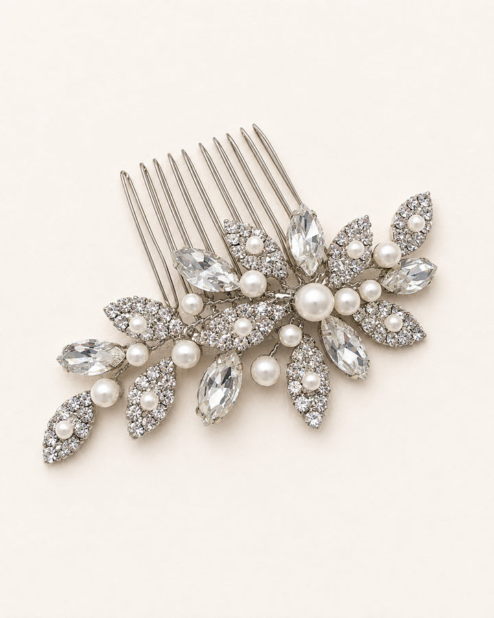 Close-up of a silver wedding comb showing rhinestone leaf clusters and a center pearl