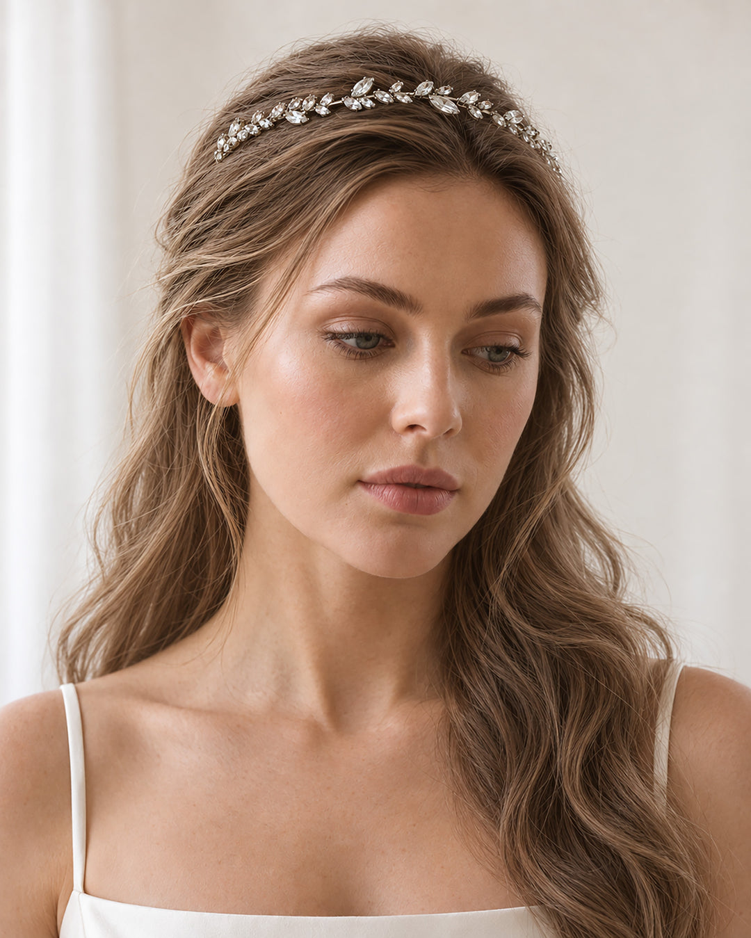 Front view of a bride with long half-up waves wearing the delicate Priya headband