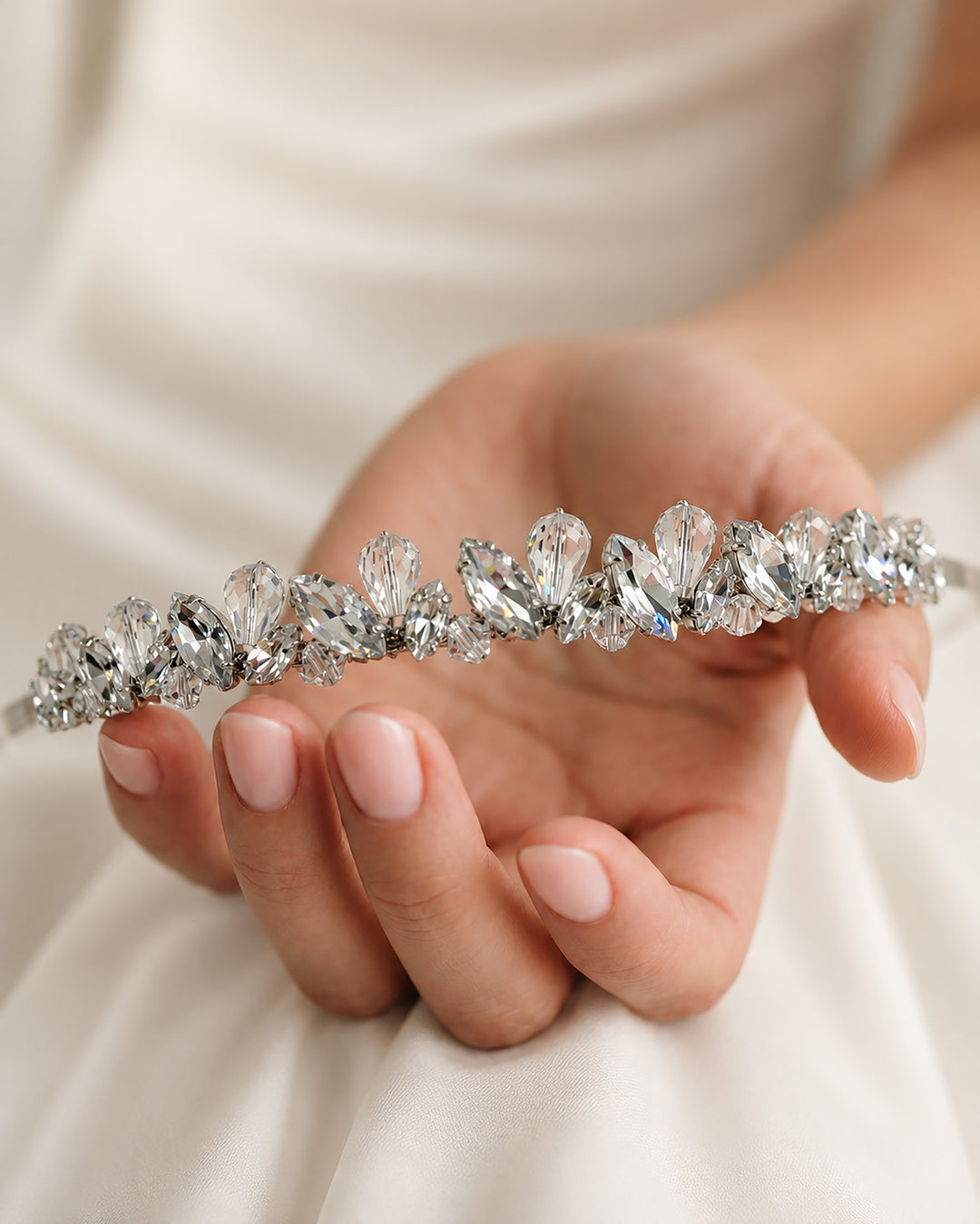 Hand holding a slim hand-wired silver bridal headband with marquise rhinestones and crystal teardrops