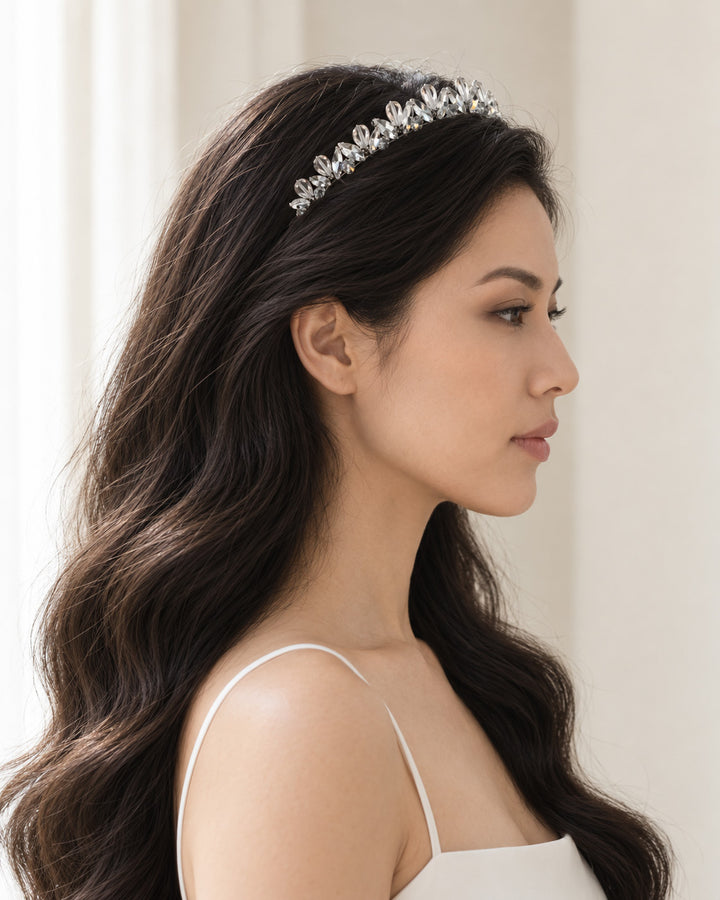 Side profile of a bridal look with long dark waves and a delicate silver crystal headband