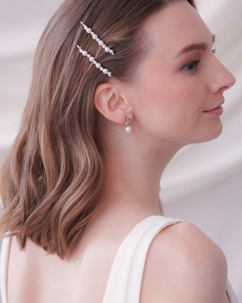 Bride with shoulder-length waves wearing two pearl bobby pins stacked above the ear