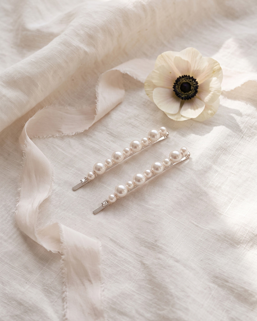 Two pearl bobby pins on ivory linen with silk ribbon and a white anemone