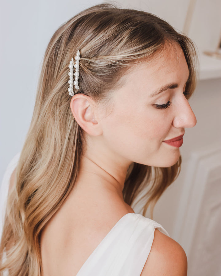 Pearl bobby pins worn as a pair above the ear in long, loose bridal waves