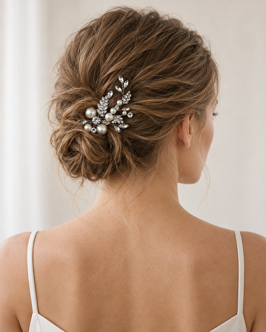 Bride with an updo wearing a silver pearl and rhinestone hair pin at the back