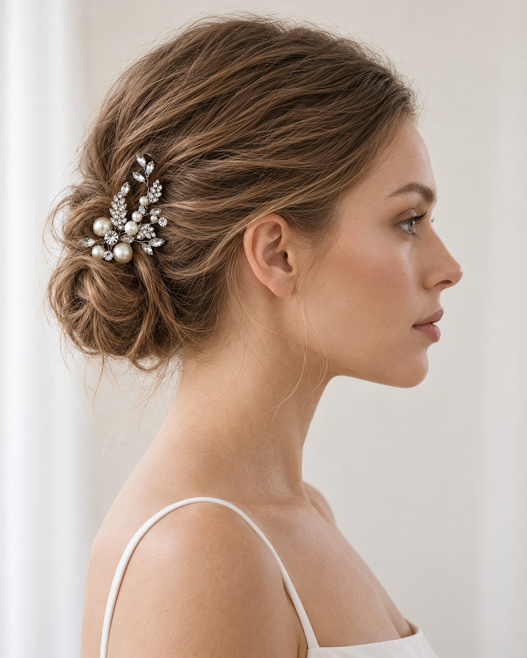 Side profile of a bride with an updo wearing a silver leaf and pearl hair pin