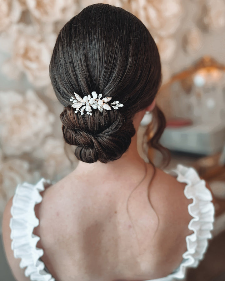 Bride wearing gold freshwater pearl floral wedding hair pin in bridal updo hairstyle