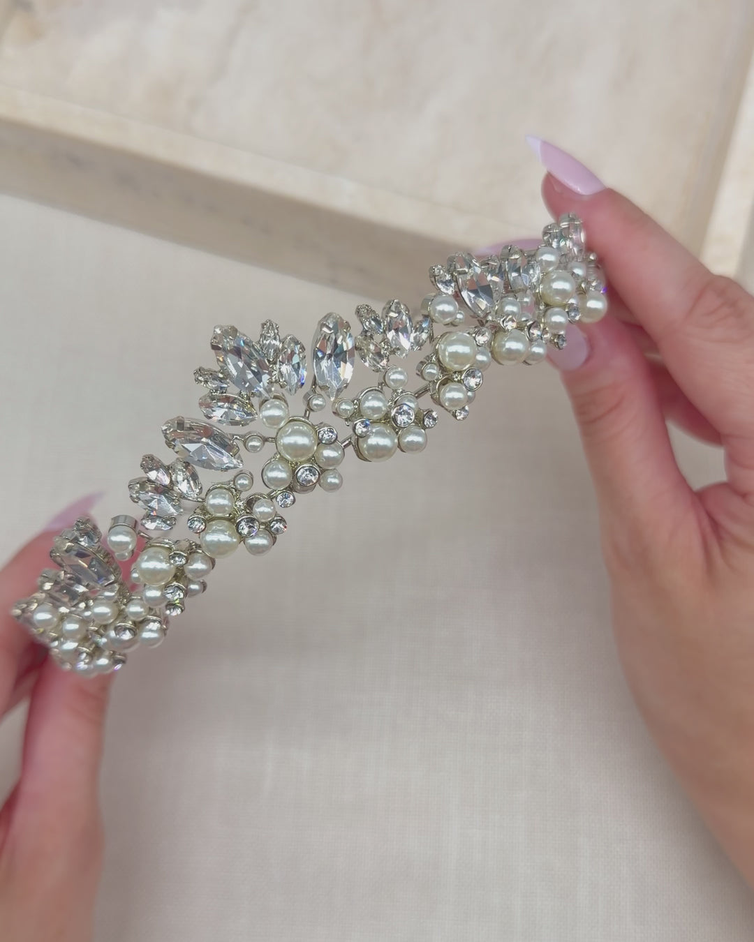 Video of a silver bridal tiara with a marquise rhinestone and pearl clustered center peak