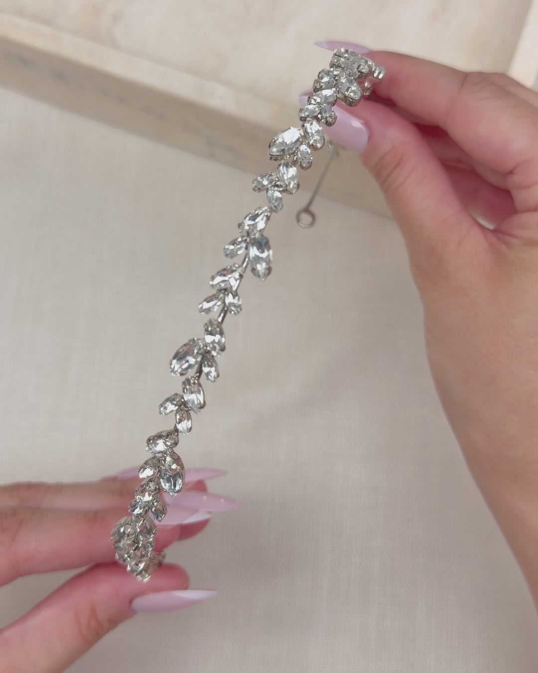 Hands holding the Priya headband to show how slim and lightweight its rhinestone leaf vine is