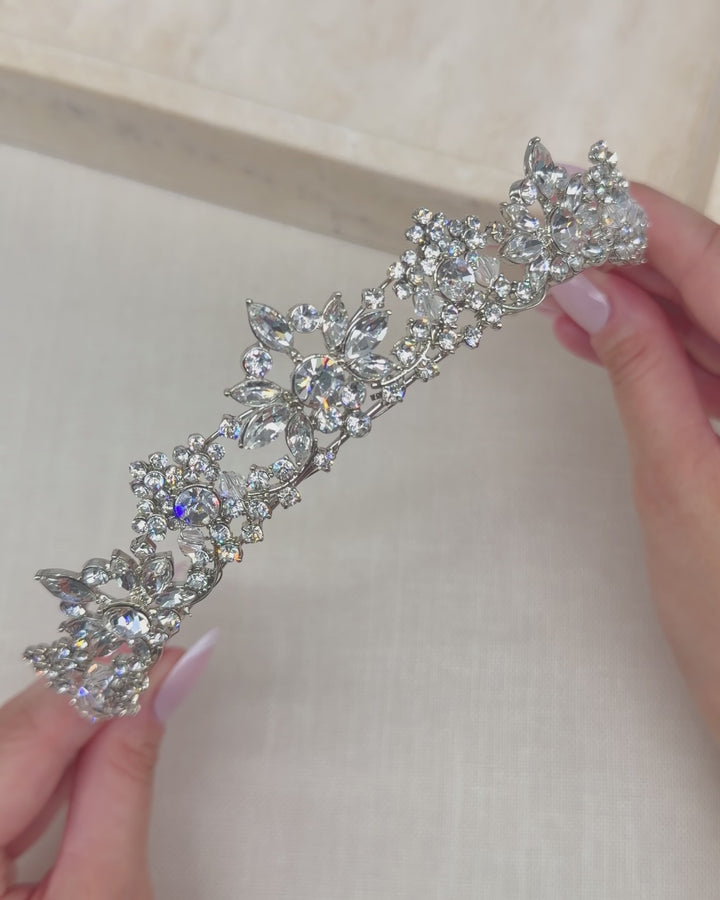 Video of a silver bridal tiara with rhinestone floral clusters rising to a center peak